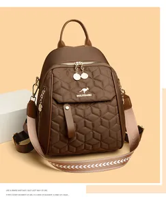 Close-up of brown quilted backpack featuring a metallic logo and a wide patterned strap