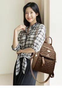 Detail of coffee brown quilted backpack featuring a metallic kangaroo logo and woven strap