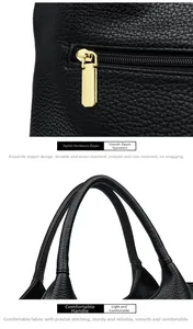 Polished gold metal zipper pull and textured black leather handles on a commuter bag