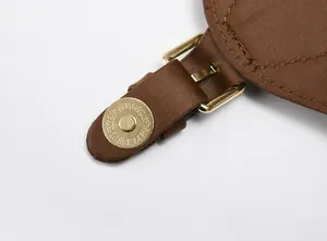 Détail du fermoir magnétique doré sur le rabat en cuir marron du sac à dos matelassé