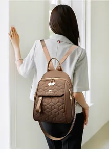 Close-up of quilted coffee brown backpack with golden kangaroo logo and zip detail