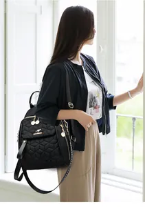 Detail of black quilted backpack with kangaroo logo and gold metallic hardware on a model