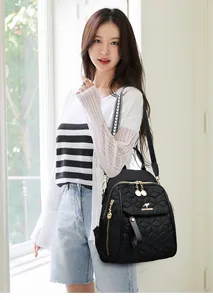On-body shot of a black quilted backpack featuring golden kangaroo logo and hardware
