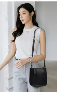 Detailed view of black lychee grain leather crossbody bag with gold hardware and strap