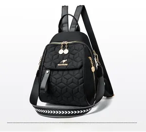 Detail view of black quilted nylon backpack with gold hardware and geometric woven strap