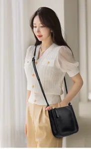 Close-up of a minimalist black lychee pattern leather shoulder bag on a female model