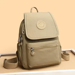 Mini mochila de nailon caqui con solapa y correas ajustables sobre fondo cálido