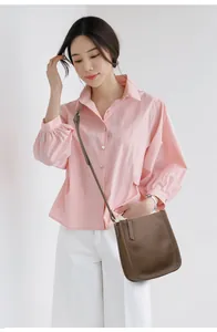 Brown litchi grain leather crossbody bag shown on model with adjustable strap detail