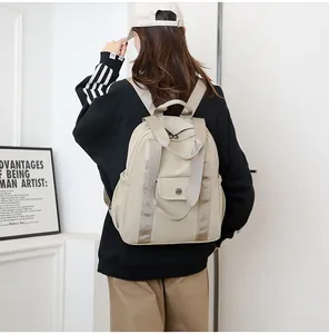 Rückansicht eines Models mit einem beigen wasserfesten Nylon-Rucksack im minimalistischen Raum