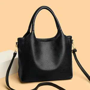 Elegant black lychee grain leather handbag with gold hardware and shoulder strap
