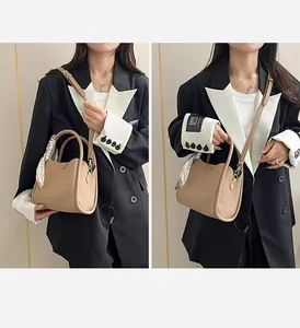 Detail view of khaki pebbled leather bucket bag with decorative silk scarf and strap