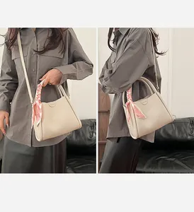 Close-up of beige lychee grain leather bucket bag with floral scarf handle and shoulder strap