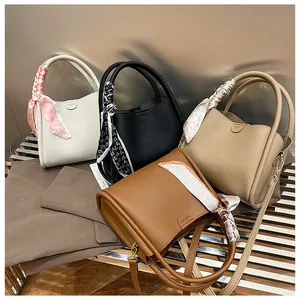 Detail of multi-color leather bucket bags with scarf decor and embossed brand logo
