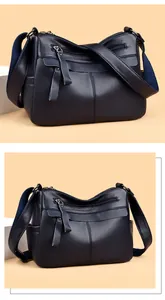 Detail of navy lychee pattern leather handbag with tassel zipper and wide fabric strap