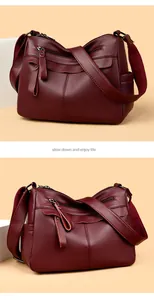 Detailed view of dark burgundy leather crossbody bag with multiple zipper pockets and tassels