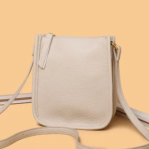 Beige pebble leather crossbody phone bag with gold metal rings and zipper closure