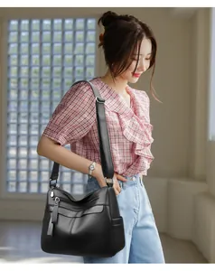 Close-up of black litchi pattern leather bag featuring multiple zipper pockets and wide strap