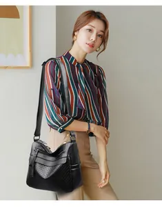 Detail of black quilted leather shoulder bag with multiple zip pockets on a model