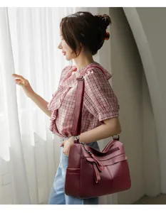 Close-up of wine red pebble grain leather crossbody bag with multi-zip compartments