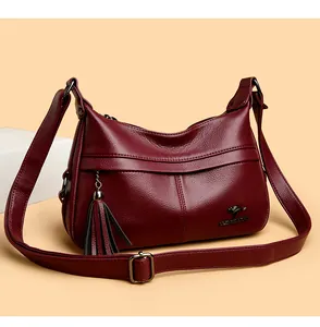 Detail of dark red crescent bag showing lychee pattern leather and tassel charm