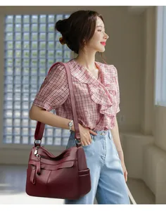 Detail of burgundy lychee grain leather crossbody bag with multiple zipper pockets