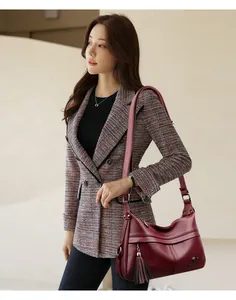 Close-up of wine red pebble leather handbag featuring tassel detail and kangaroo logo