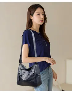 Detail of dark blue leather crossbody bag with woven texture on a fashion model