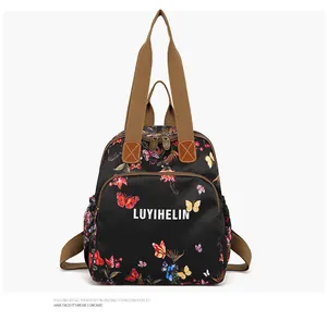 Detail of vibrant butterfly print on black nylon multi-functional backpack with brown handles