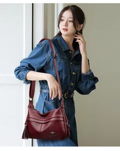 Detail of burgundy pebbled leather hobo bag with tassel and adjustable metal buckle strap
