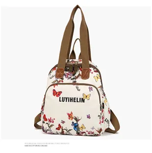 Detailed close-up of dual metal zippers and butterfly print on a cream canvas backpack