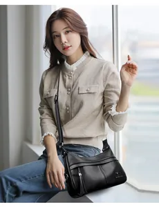 Close-up of black leather crescent bag featuring kangaroo logo and tassel detail
