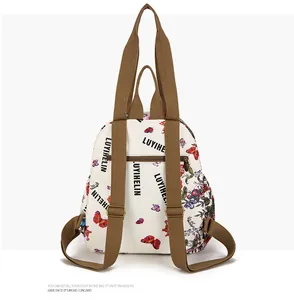 Detail of backpack back with floral prints, brown canvas straps and hidden zipper pocket