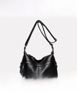 Detail of black pebbled leather crossbody bag with metal kangaroo logo and tassel charm