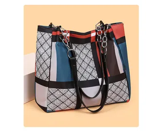 Detail of quilted tote bag featuring colorful patchwork and metal chain shoulder strap