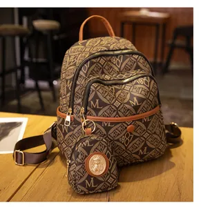 Detalle de mochila vintage marrón con monograma, mini estuche y herrajes dorados