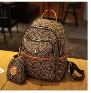 Detalle de mochila vintage marrón con monograma y colgante de retrato de medusa dorado