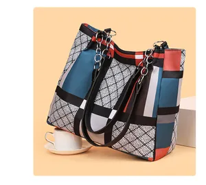 Detail of color-block geometric tote bag with silver chain straps on warm backdrop