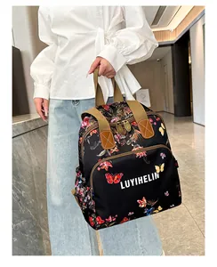 Detail of floral print backpack featuring white lettering and brown leather accents