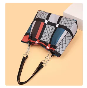 Detail of color-block geometric tote bag with diamond lattice pattern and chain strap