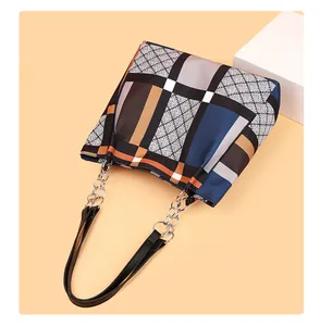 Detail of multi-color geometric patchwork tote bag with silver metal chain straps