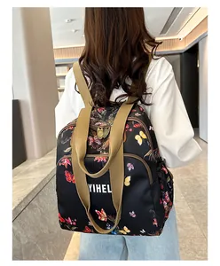 Detail of floral butterfly print on a black backpack with YIHELI logo and beige strap