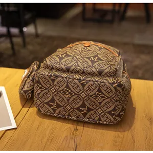 Vista detallada de la mochila marrón vintage con monograma y monedero pequeño a juego