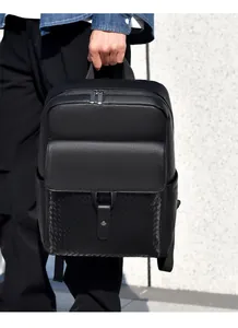 Détail de la texture en cuir tressé et du grain litchi sur un sac à dos noir pour homme
