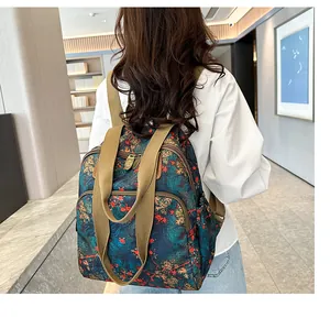 Detailed back view of a floral vintage backpack with khaki straps on a female model