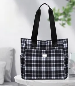 Détail d'un grand sac cabas à carreaux avec poche avant et anses en toile noire