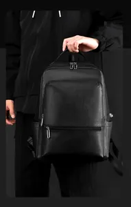 Close-up of premium black litchi grain leather texture and metallic zippers on men's backpack