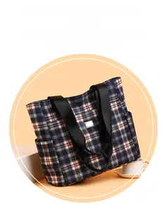 Détail du sac cabas en tissu à carreaux avec logo en métal et poche latérale