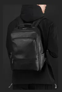 Detailed back view of a black leather business backpack with metallic silver zippers