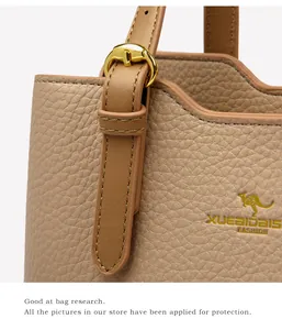 Dettaglio della pelle a grana litchi color cammello con fibbia dorata su borsa a mano