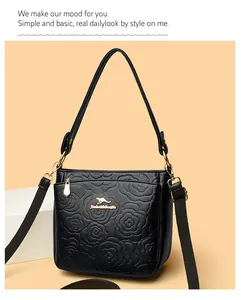 Detail of black leather bucket bag with embossed rose pattern and golden logo